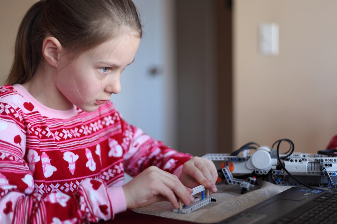 Little girl assembling a lego robot crocodile.