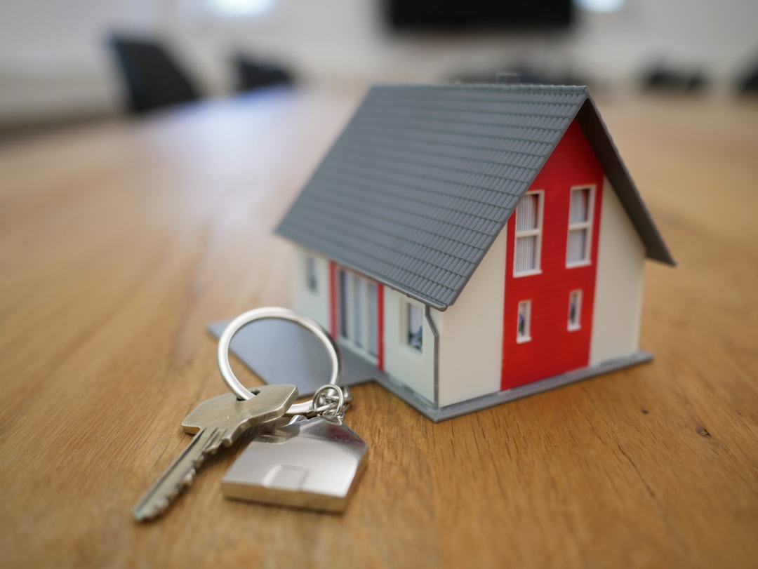 Miniature house model and a set of keys on a wooden table — the cliché image of home buying, used here as such.